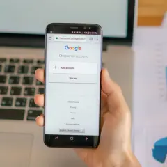 Dłoń trzyma smartfon z ekranem logowania Google.