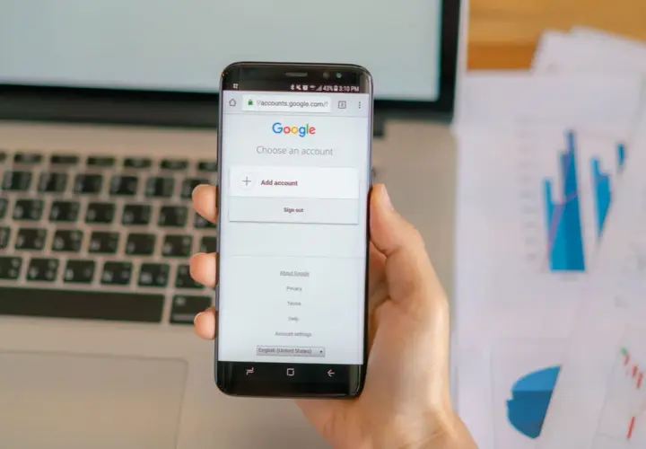 Dłoń trzyma smartfon z ekranem logowania Google.