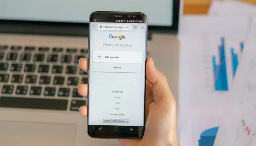 Dłoń trzyma smartfon z ekranem logowania Google.